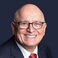 Dr. Tamaro headshot in a black suit with red tie